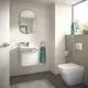 Moderne Badezimmeransicht mit einem Wandwaschtisch und Chrom-Armatur, einem WC und einem großen Fenster, das Tageslicht hereinlässt. Ideal Standard Produkte sind sichtbar.